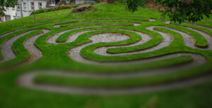 A grassy labyrinth shown in a partially-loaded photo that is clear on the top and blurry at the bottom